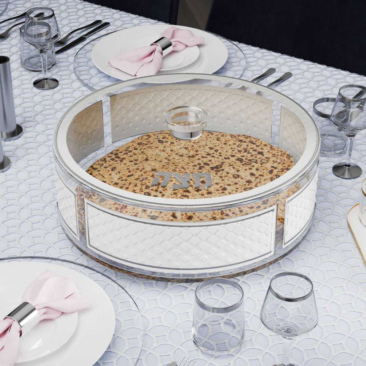 Silver matzah box holding round matzos on a Seder table with pink napkins