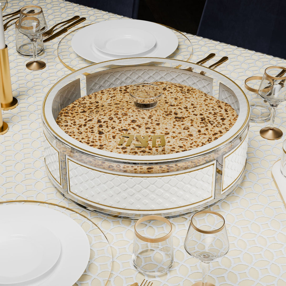 Gold matzah box filled with matzos on a cream table with gold-rimmed glasses
