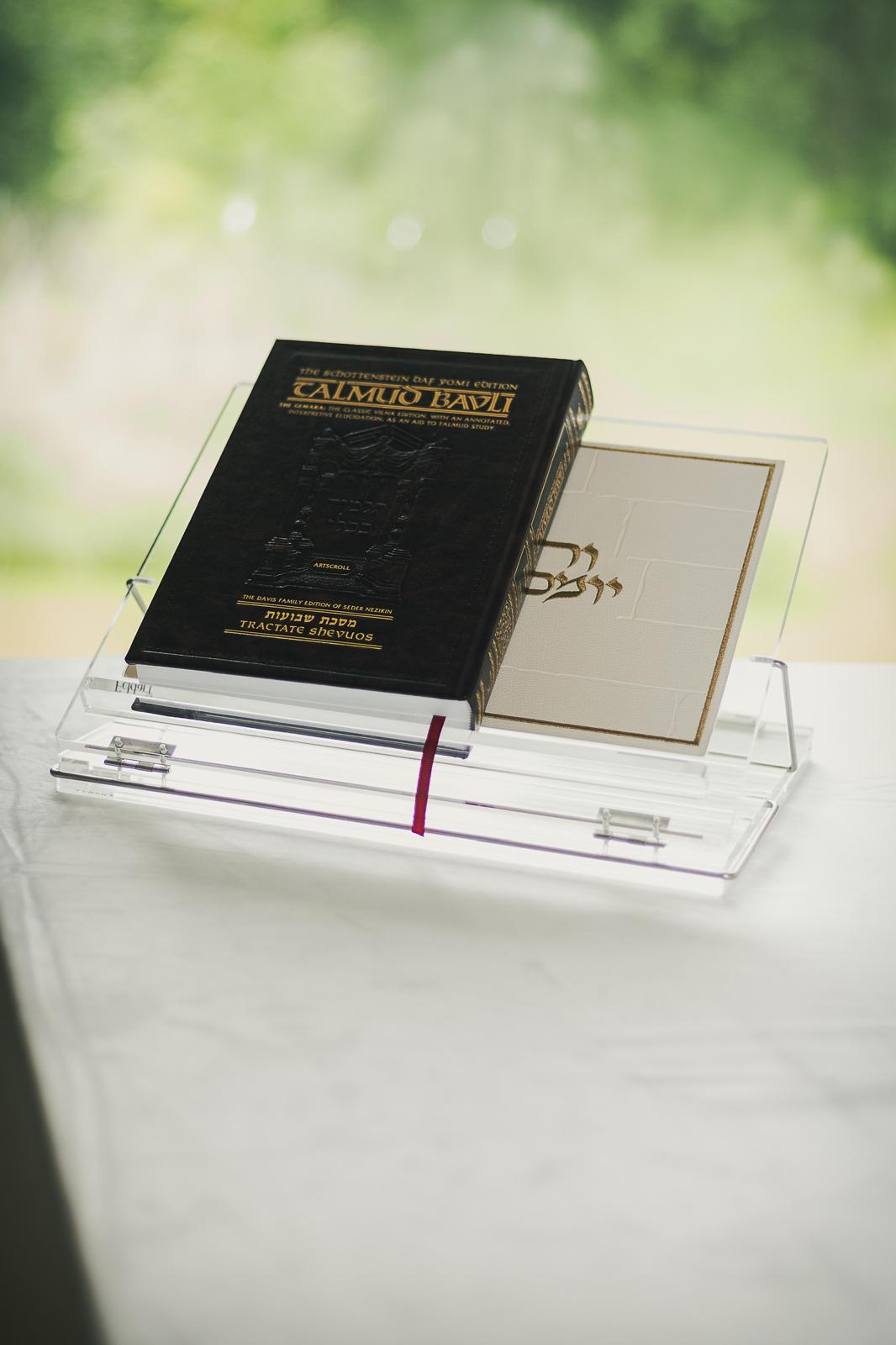 Shtender holding a Schottenstein Talmud Bavli volume by a bright window