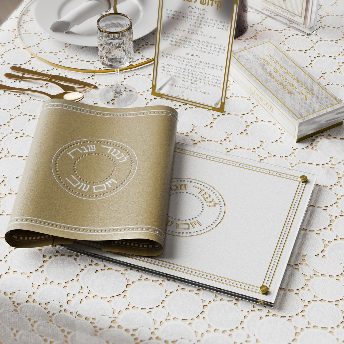 Gold challah cover rolled beside a matching challah board on a lace-covered Shabbos table