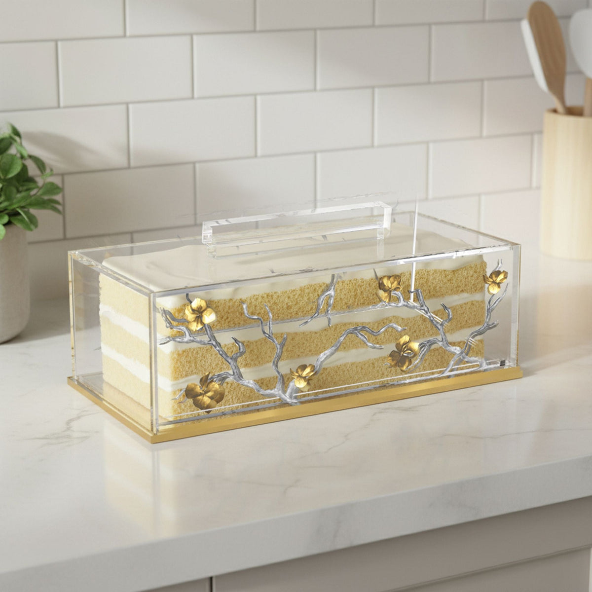 Holder with a layered sponge cake inside on a kitchen counter, lid handle on top
