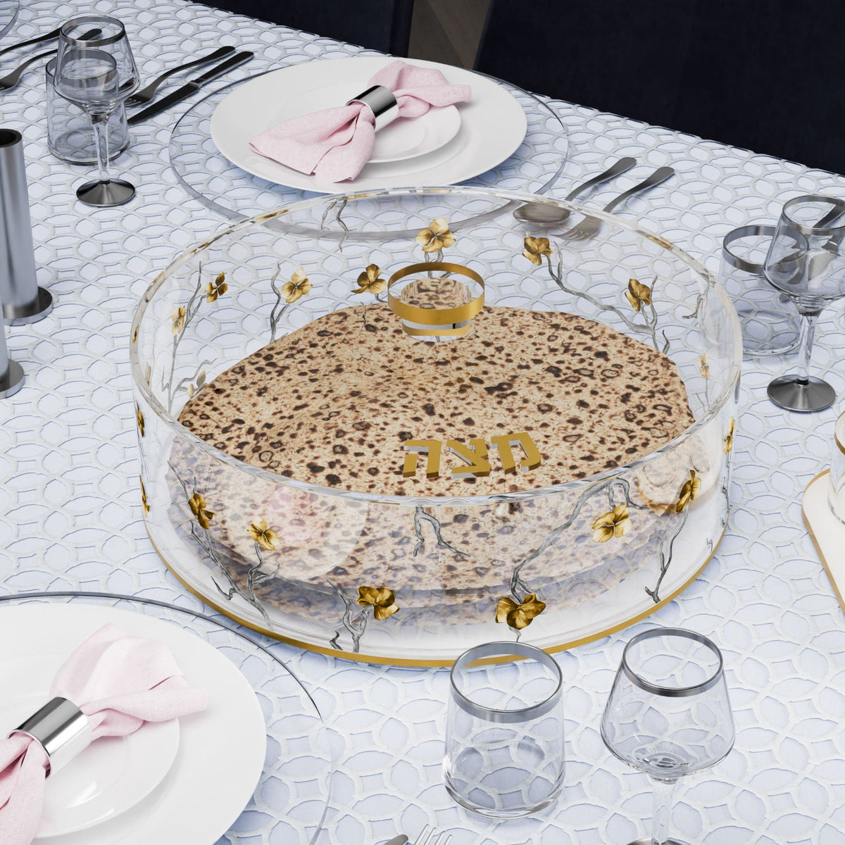 Matzah box holding round matzos on a set seder table with silver-rimmed glasses and pink napkins