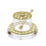 Round lucite honey jar with gold honeycomb lid and ring on a clear base, honey dipper in its slot