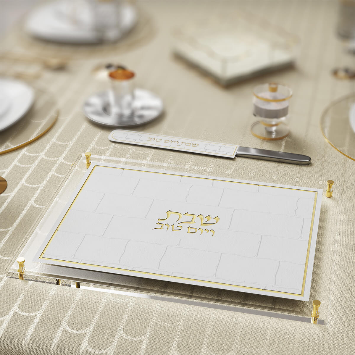 Gold Kosel challah board on a set table with a matching knife, silver kiddush cup and glasses