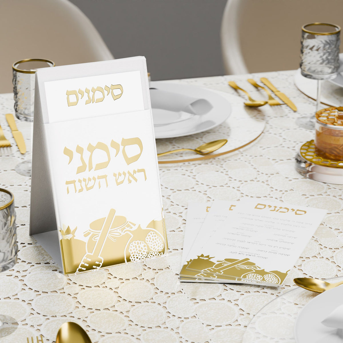 Gold simanim pouch and cards on a lace-covered Rosh Hashanah table with honey and gold flatware