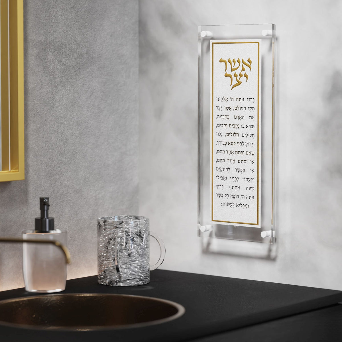 Gold Asher Yatzar plaque mounted on a grey wall above a sink and faucet