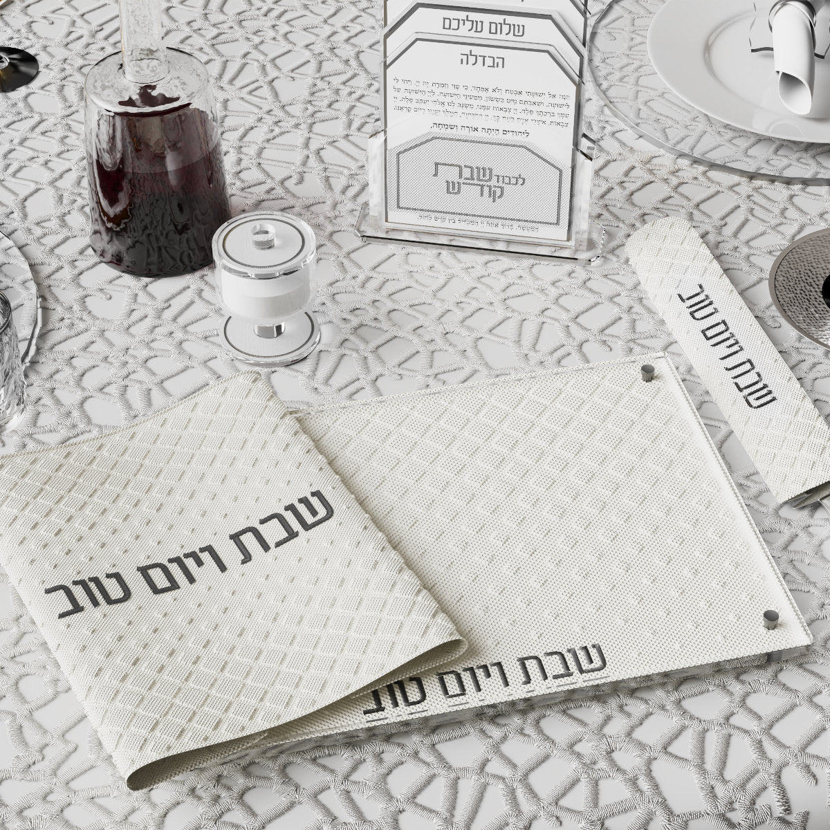 Quilted white challah cover and board with silver Shabbos V'Yom Tov lettering on a set table