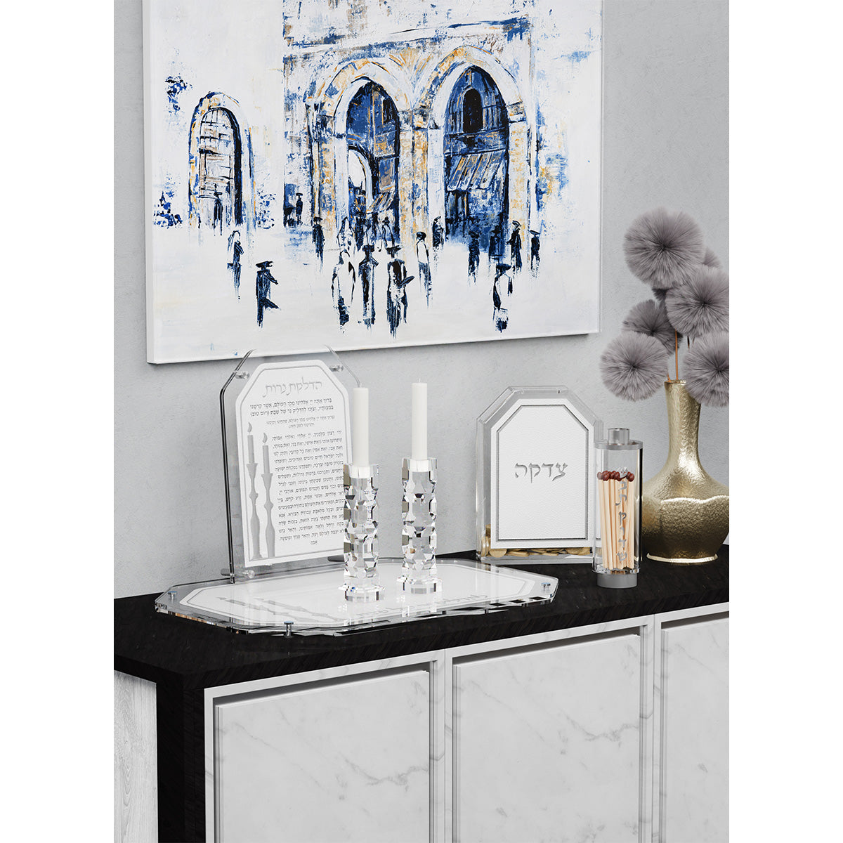 Silver tray with candlesticks, card and tzedakah box on a black and marble sideboard