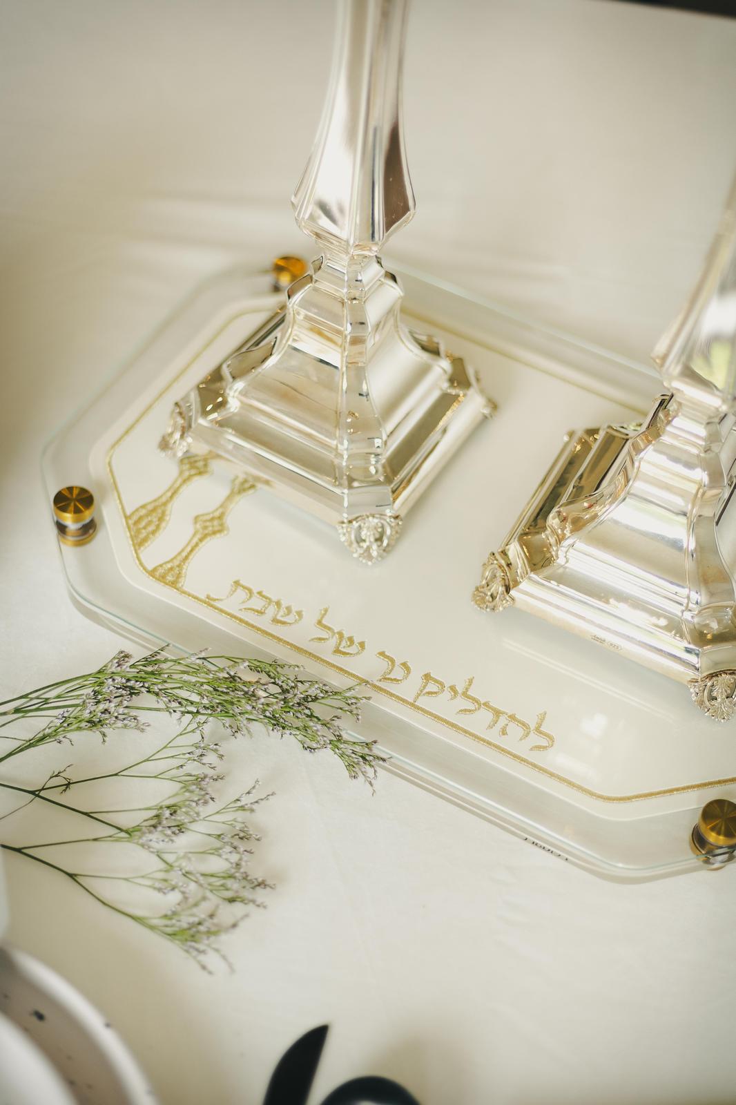 Close view of glass candlesticks standing on the gold tray's embroidered lettering