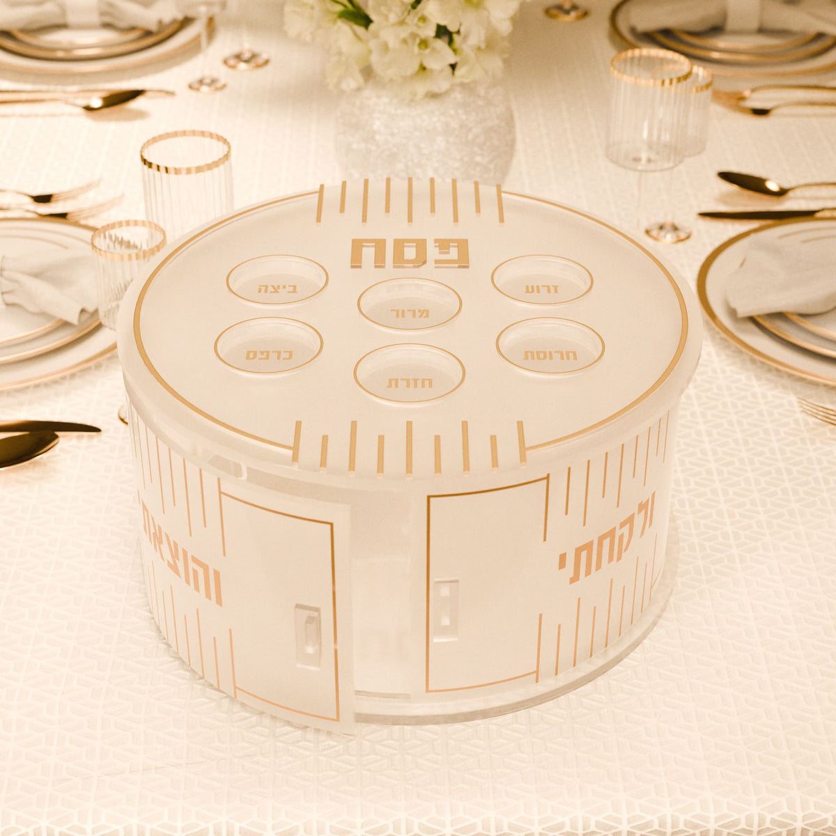 Gold tiered kearah on a set Seder table, V'hotzeisi and V'lakachti lettering beside the doors