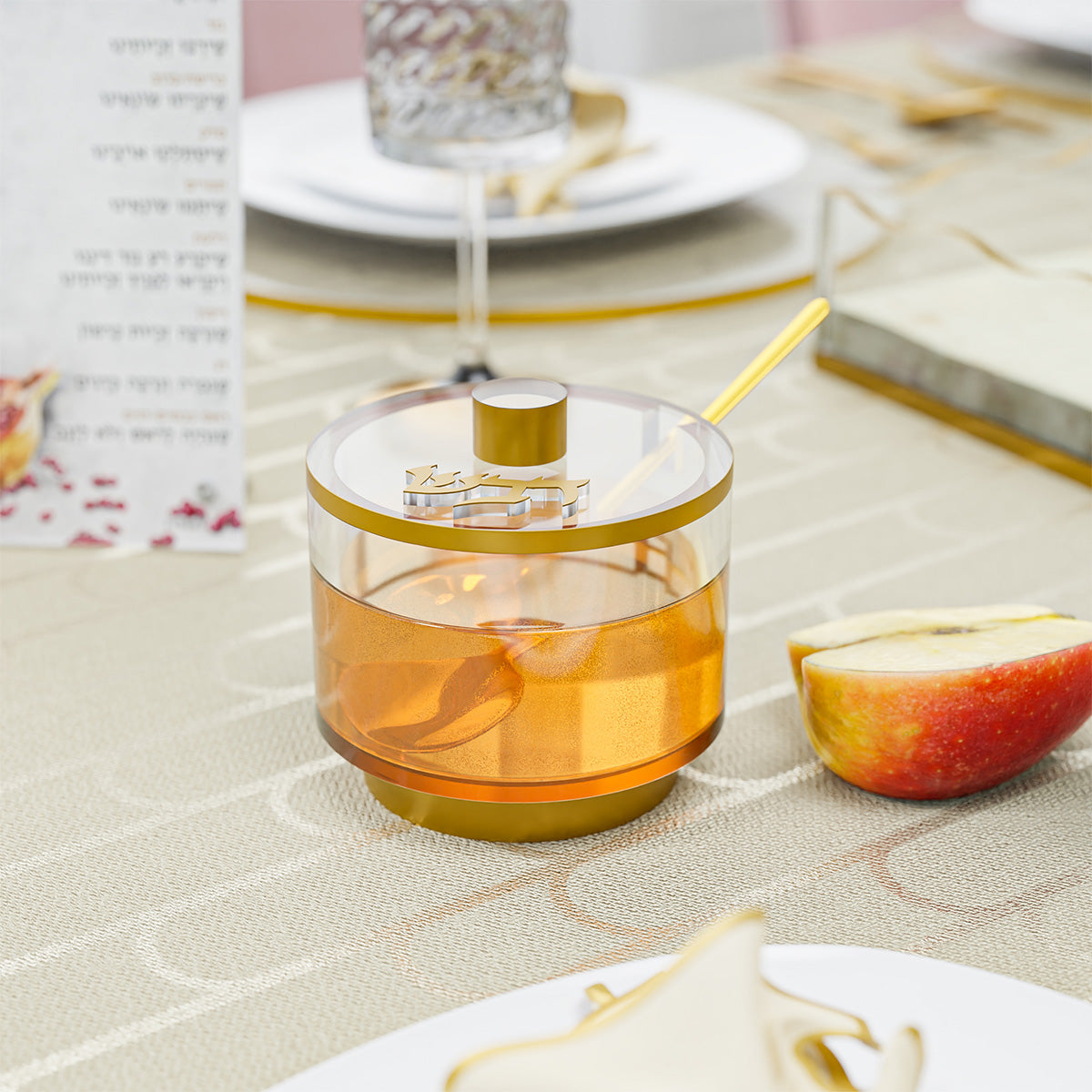 Honey dish filled with honey on a Rosh Hashanah table next to a cut red apple