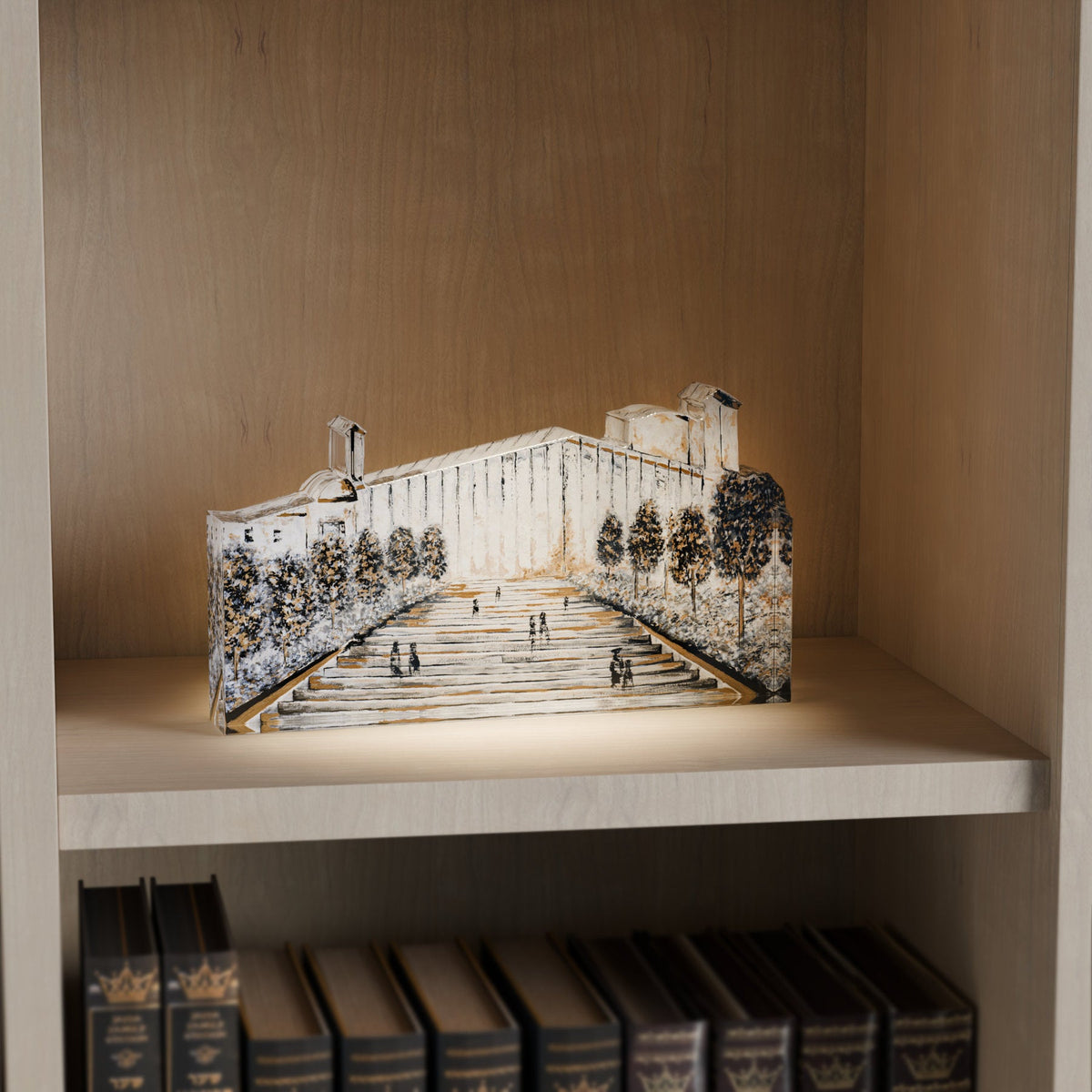 Mearas Hamechpela block lit on a bookshelf above a row of leather sefarim