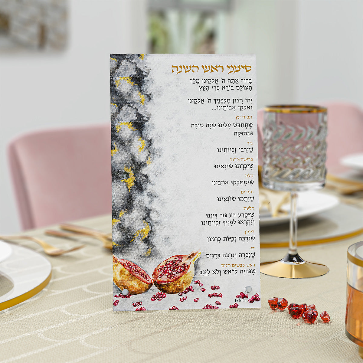 Pomegranate Simanim card at a Rosh Hashanah place setting with a gold-rim wine glass and seeds