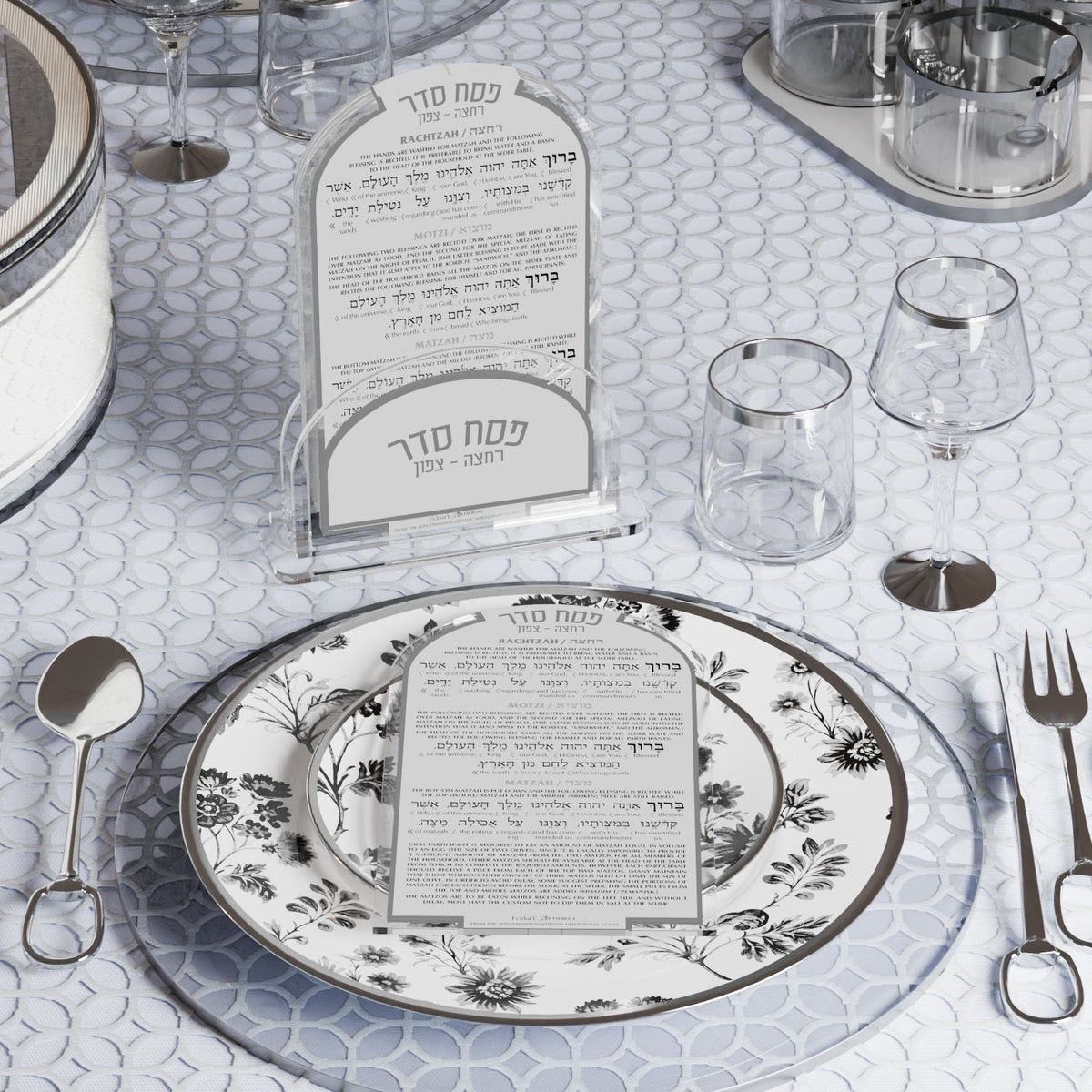 Silver version of the Seder cards at a place setting with silver cutlery and a floral plate