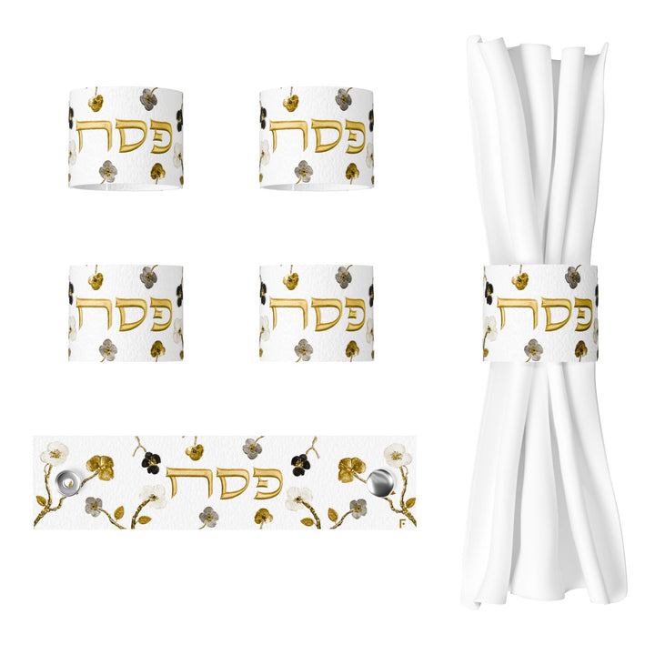 Four Ornate Garden napkin rings with gold Pesach lettering, one laid flat and one wrapped around a white napkin
