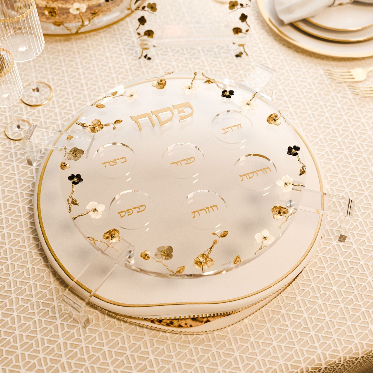 Seder plate on its legs over a matzah cover on a gold-patterned Seder tablecloth