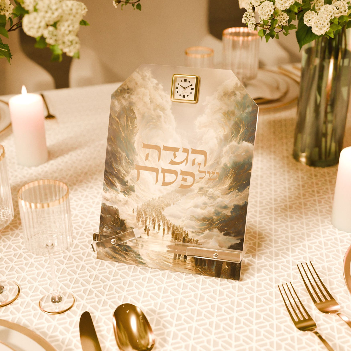 Haggadah stand on a Seder table with candles, white flowers, ribbed glasses and gold cutlery