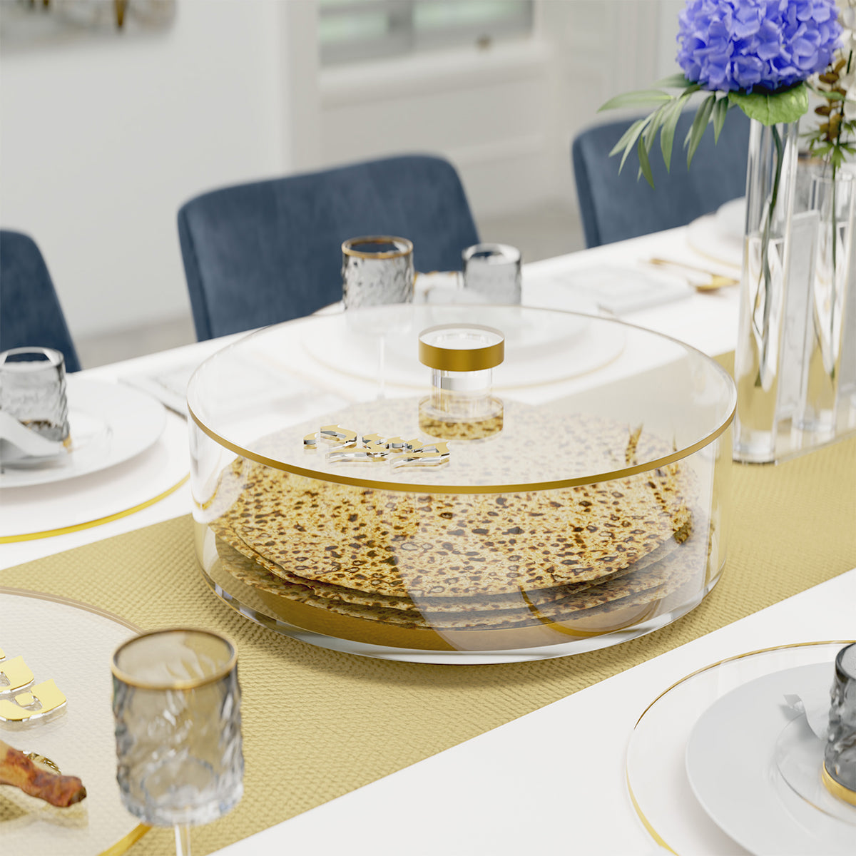 Gold-trimmed matzah box full of round matzos on a set Pesach table with a gold runner