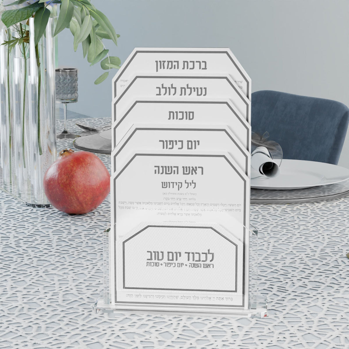 Silver Tishrei card set on a lace tablecloth with a pomegranate and silver-rimmed plates