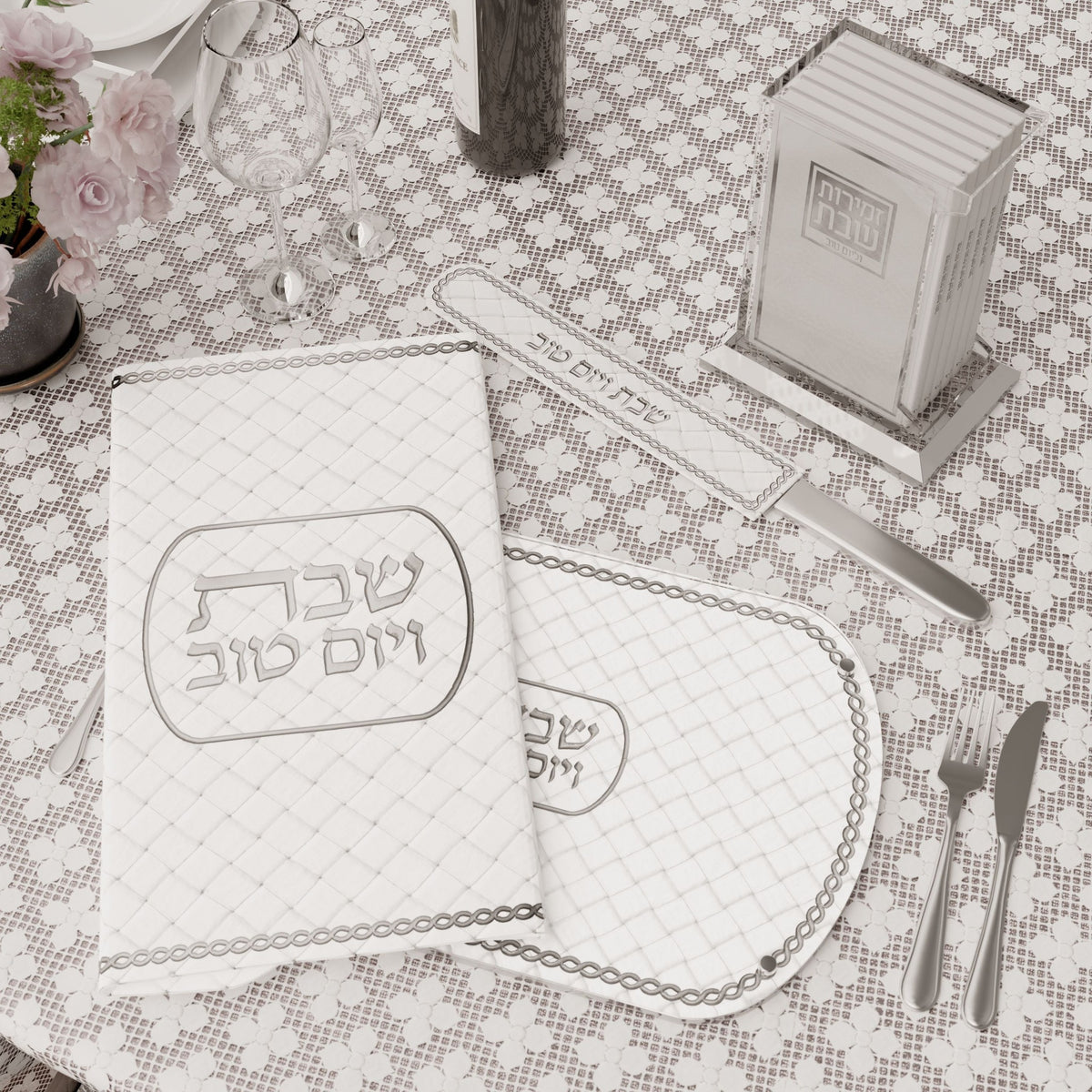 Silver knife cover with the matching challah cover and silver zemiros holder on a set table