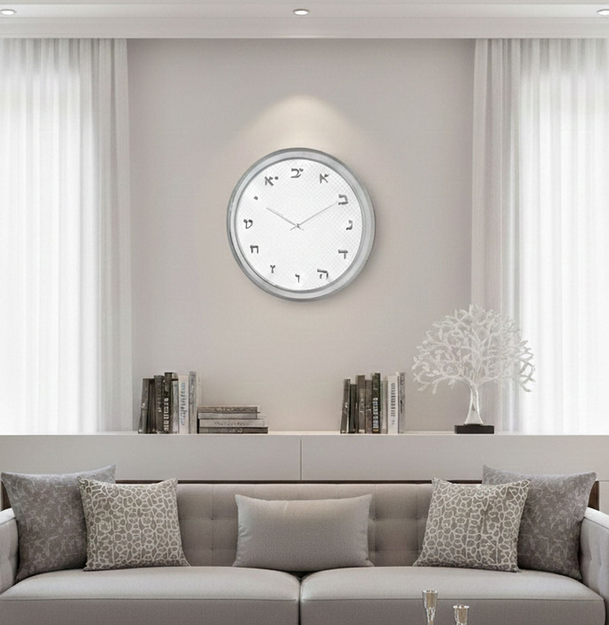 Silver Hebrew letter clock on a grey living room wall above a shelf and sofa