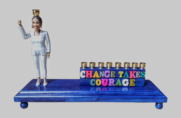AOC menorah — congresswoman figure on blue platform with Change Takes Courage letters | Judaica Square Lakewood