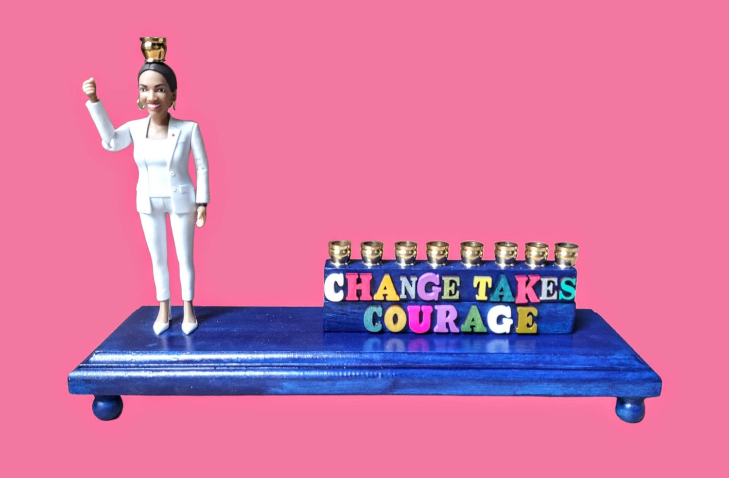AOC menorah — congresswoman figure on blue platform with Change Takes Courage letters | Judaica Square Lakewood (view 3)