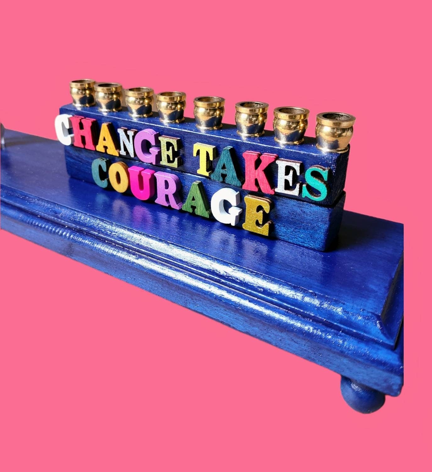 AOC menorah — congresswoman figure on blue platform with Change Takes Courage letters | Judaica Square Lakewood (view 5)