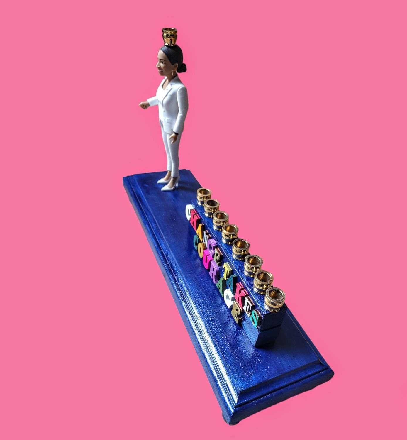 Senator AOC menorah — action figure raising the shamash beside carved wood letters | Judaica Square Lakewood (view 4)