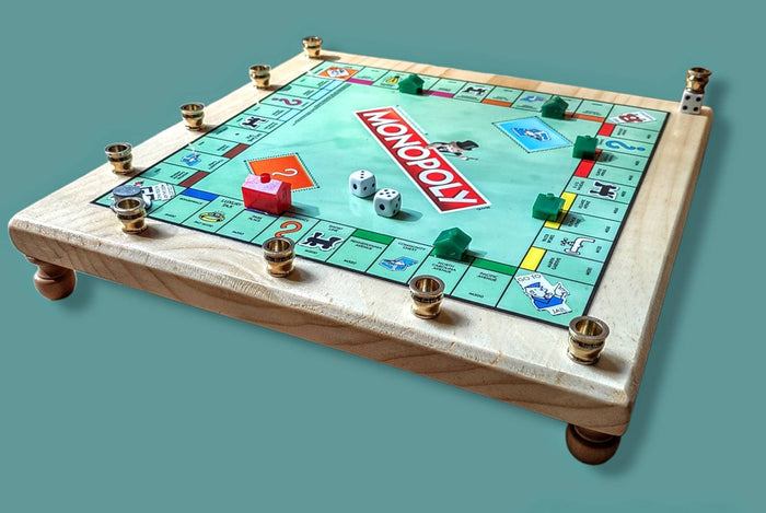 Monopoly menorah — repurposed game board and tokens on stained wood with brass cups | Judaica Square Lakewood
