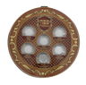 Round brown and gold seder plate with six clear cups labelled in Hebrew and English, top view