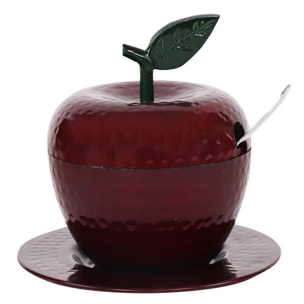 Deep red hammered apple-shaped honey dish with green leaf lid handle, spoon and matching red tray