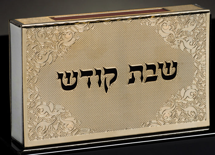 Gold engraved match box cover with black Shabbat Kodesh lettering and scrollwork corners