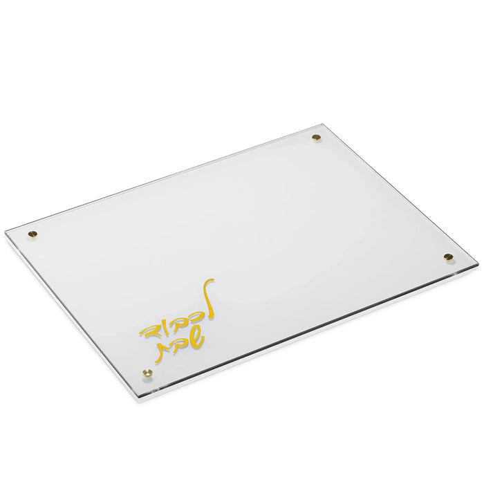White challah board with gold Hebrew L'kavod Shabbos script and gold corner pins, angled view