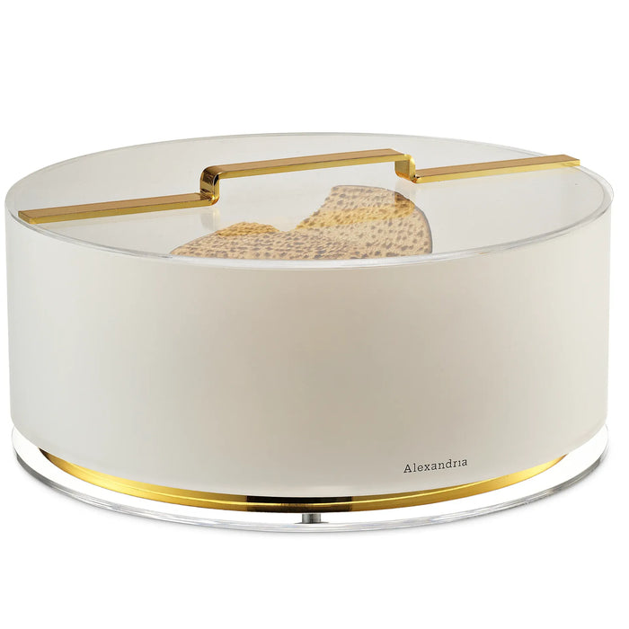 Round ivory acrylic matzah box with clear lid, gold bar handle and gold ring at the base