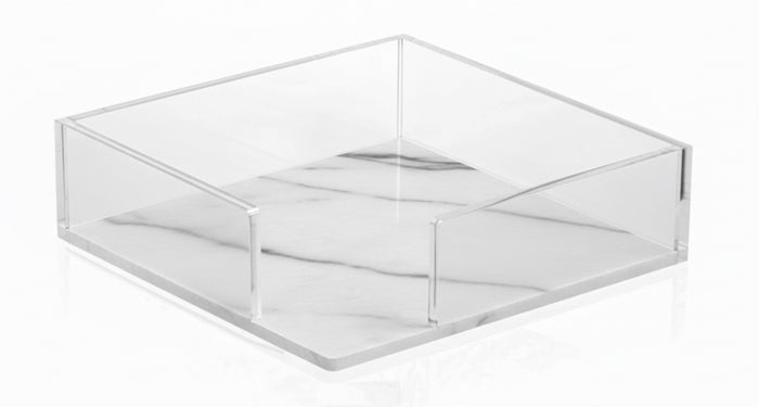 Square napkin holder with clear sides on a white marble base with soft grey veining