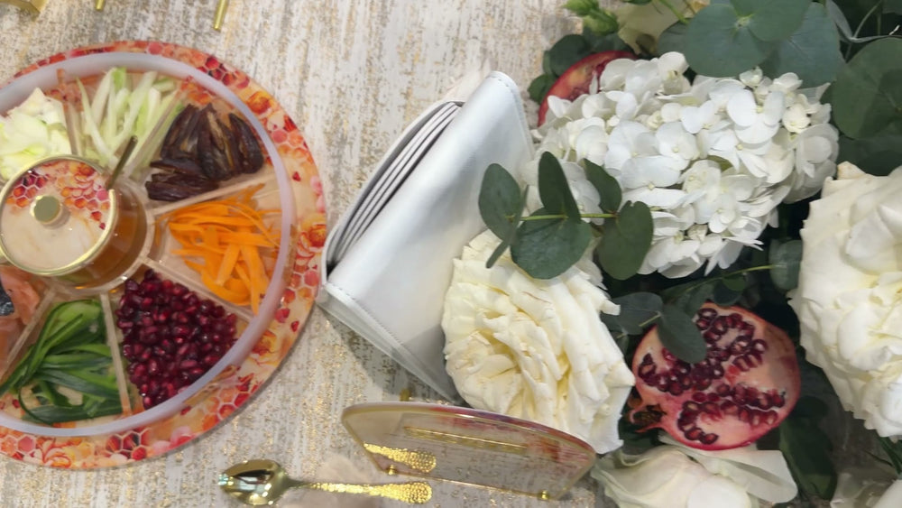 Rosh Hashanah table with honey dishes, apples, flowers and festive place settings.