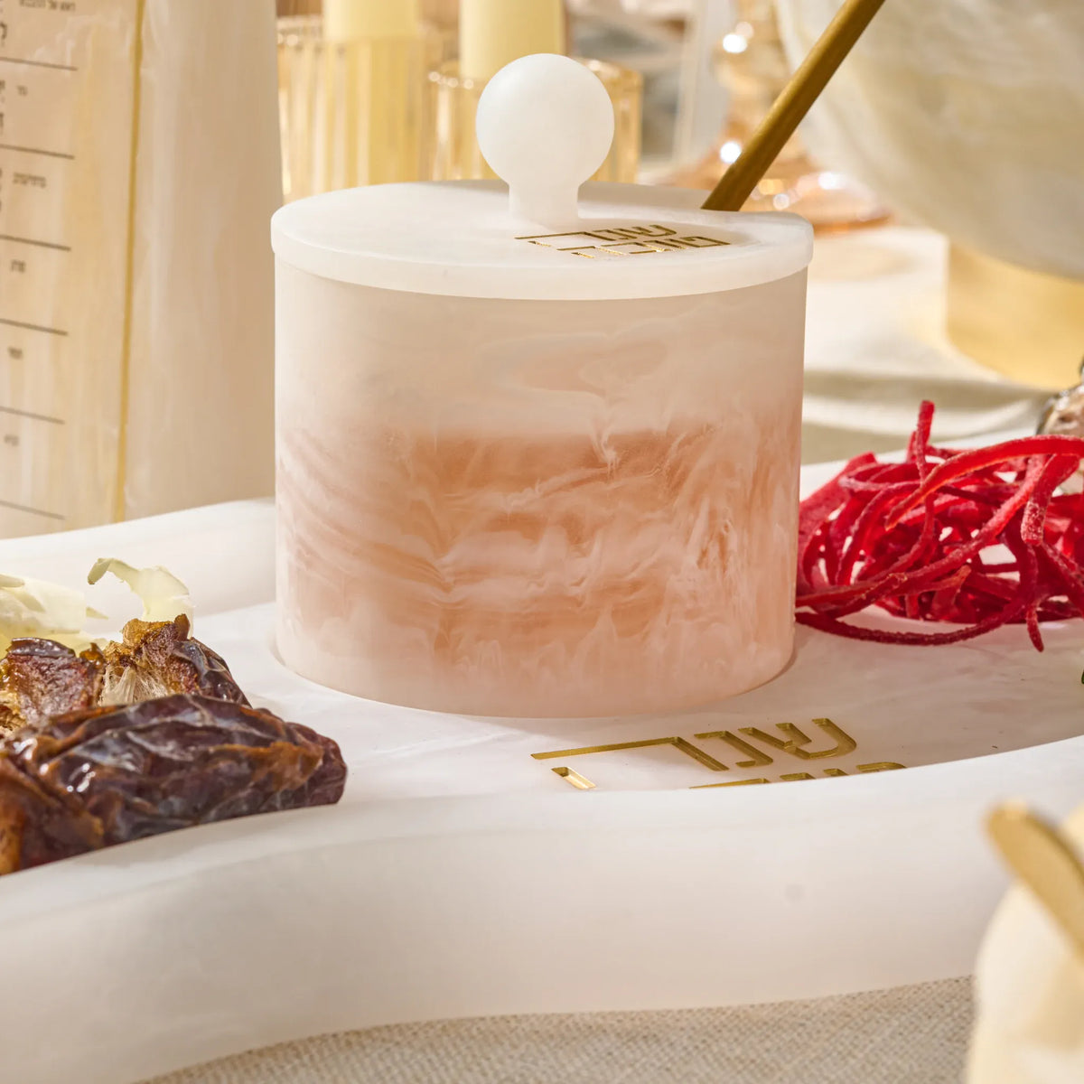 Close-up of the rose-marbled resin honey dish with dates and shredded carrot on the Simanim tray