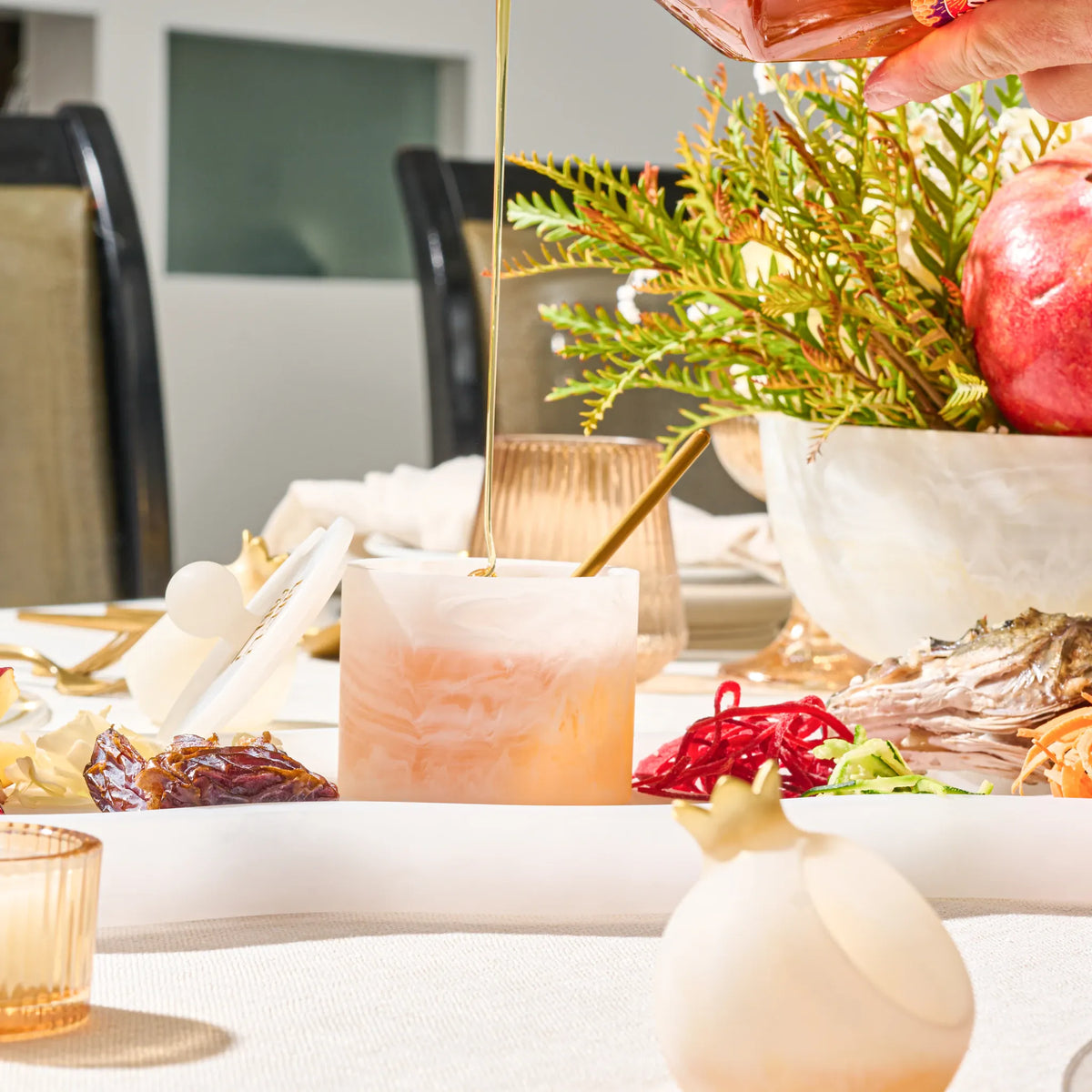 Honey poured into the resin dish beside a pomegranate arrangement on the Rosh Hashanah table