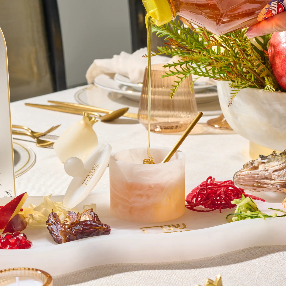 Honey being poured into the rose-marbled resin honey dish on the curved Simanim tray