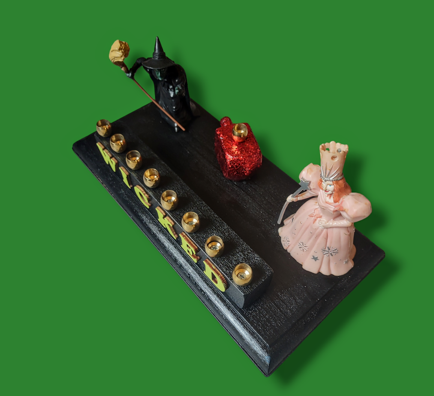 Wicked menorah — Elphaba and Glinda figures with ruby red dreidel and brass candle cups | Judaica Square Lakewood (view 4)