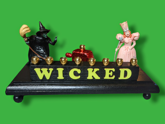 Wicked menorah — Elphaba and Glinda figures with ruby red dreidel and brass candle cups | Judaica Square Lakewood