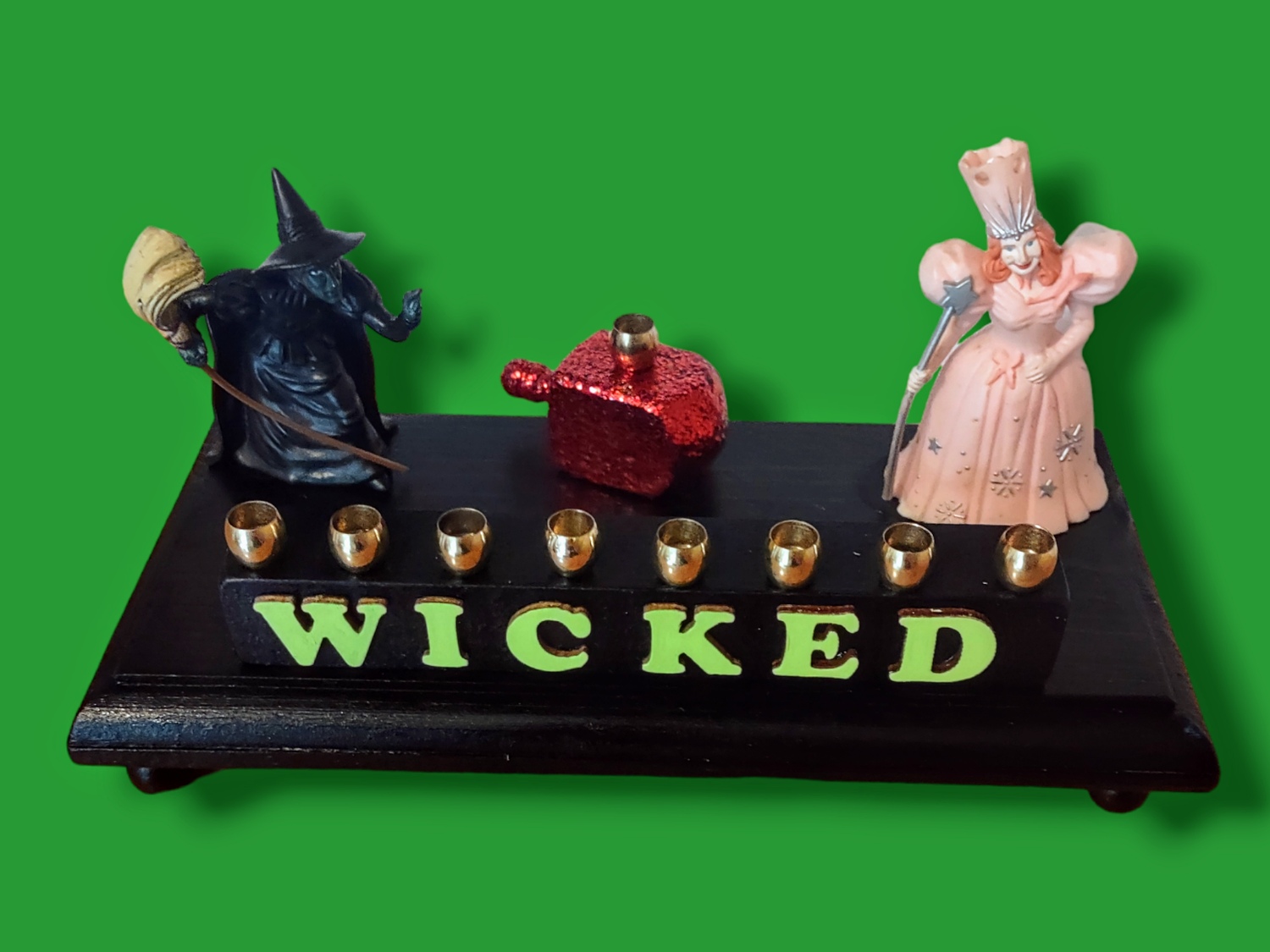Wicked menorah — Elphaba and Glinda figures with ruby red dreidel and brass candle cups | Judaica Square Lakewood (view 2)