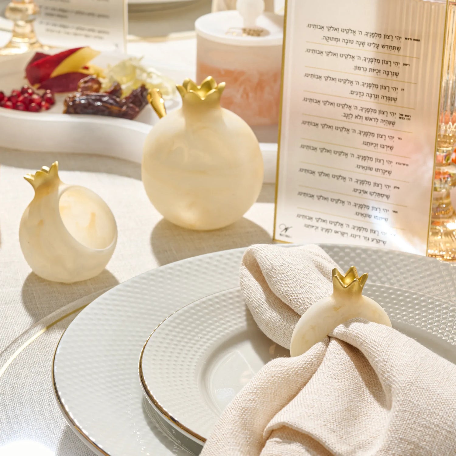 Single white resin pomegranate napkin ring with a silver-tone crown on a white background