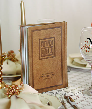 Simchonim Luvi style hardcover zemiros, shown on a table setting