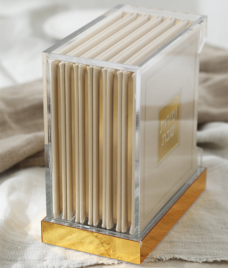 Simchonim Lucite stand holding hardcover zemiros, shown on a table setting