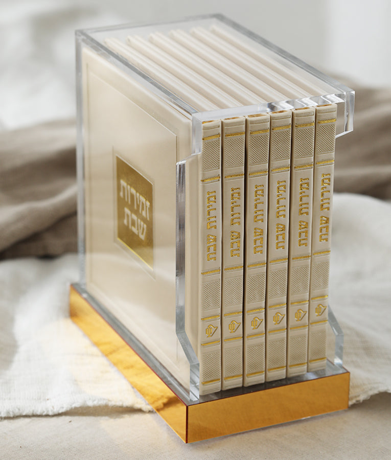 Simchonim Lucite stand holding hardcover zemiros, shown on a table setting
