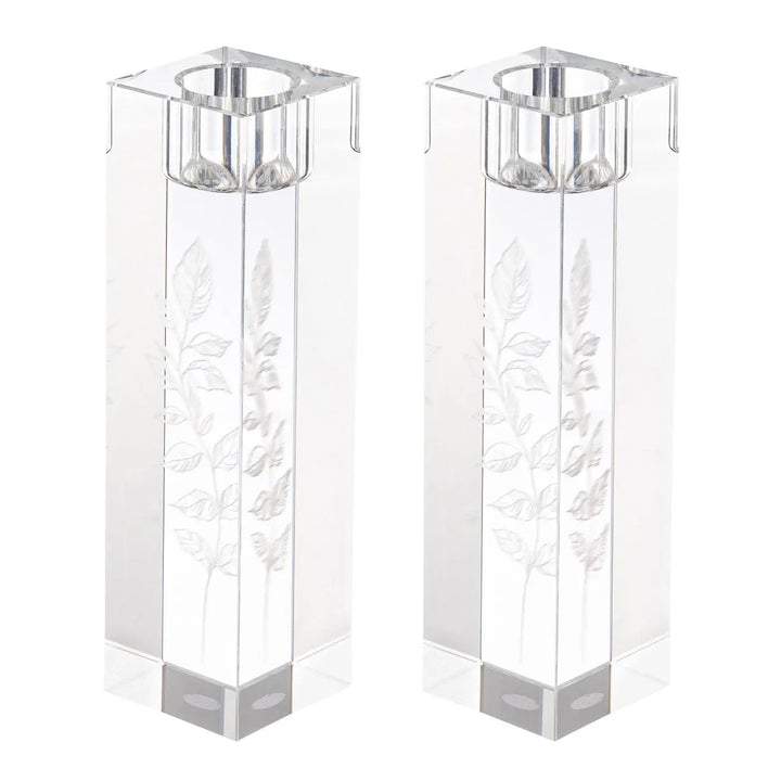 Pair of clear crystal candlesticks with engraved leaf design on a white background