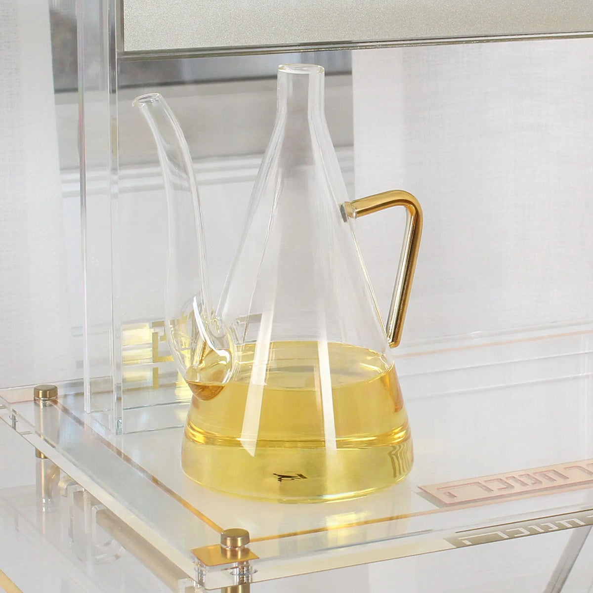 Close view of the glass oil jug filled with golden oil, standing on a lucite menorah base