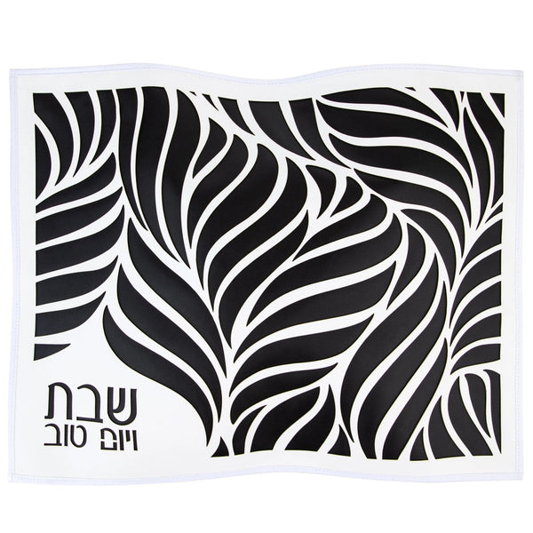 Black leather challah cover under a white cut-out leaf overlay with Shabbos V'Yom Tov corner text